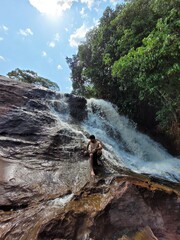 Young Man Posing Near a Waterfall in a Scenic Natural Setting with Trees and Fresh Air