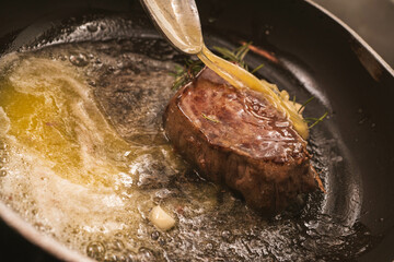 Steak cooking in a pan with butter being spooned over it for flavor. Perfect for recipe blogs, cooking tutorials, or restaurant marketing.