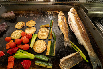 Whole fish and fresh vegetables are cooked on a grill. Ideal for seafood restaurant ads, menus, or...