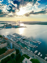 A stunning aerial view of a marina with yachts and boats, captured during a colorful sunset over the bay. Perfect for tourism campaigns, travel guides, and destination promotions.