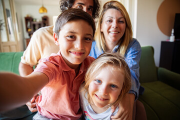 Happy family taking group selfie on couch at home