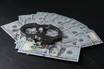 Corruption. Handcuffs and dollar banknotes on black table