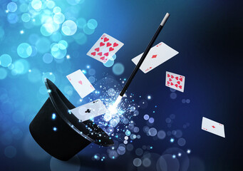 Magician's hat and wand on blue background. Magic trick with playing cards