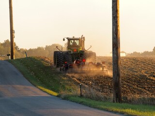 Farmer disking corn field with farm implements