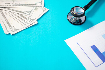 Stethoscope, US Dollar banknote and printed statistic chart. Financial, account, statistics and financial health concept.