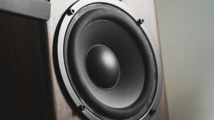 Closeup bookshelf monitor speaker with subwoofer dome and tweeter on a computer table desk. Music production, sound production, and audiophile concept.