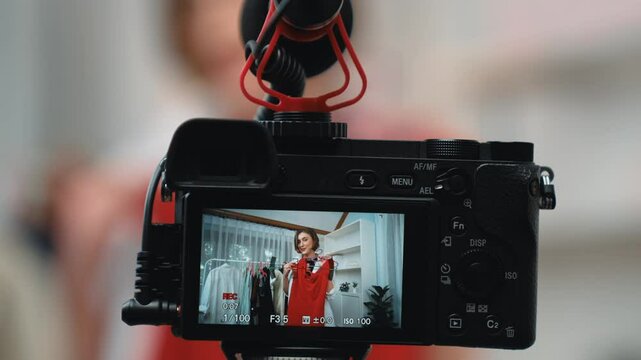Rear view behide camera screen display woman influencer shoot vlog video review clothes prim social media or blog. Girl with apparel studio lighting for live streaming marketing recording session