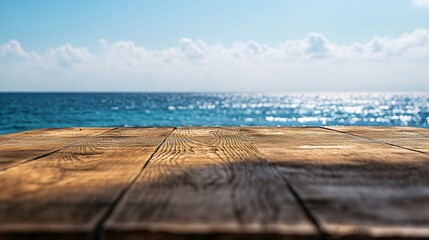 Fototapeta premium 2410 67.A wooden tabletop set against a blurred backdrop of a bright blue sea and clear sky. The tableâ€™s texture contrasts with the distant water, creating an inviting scene for enjoying a seaside