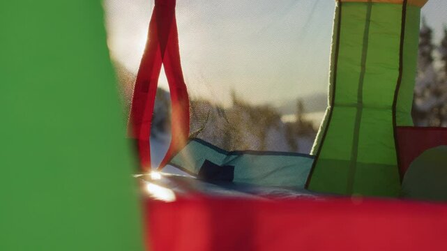 Helmeted man crawling into bounce house in winter forest