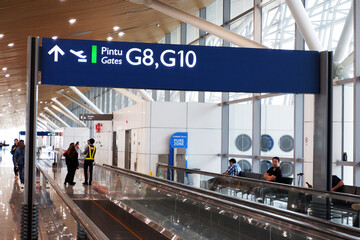 Fototapeta premium KLIA T1 or Kuala Lumpur International Airport Terminal 1 boarding gate signage on top of the moving walkways or travelator and people in the waiting area for international flight or delay in flight. d