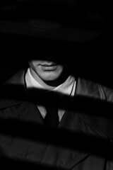 A dark silhouette of a male detective in a coat and hat with a noir style. A dramatic noir portrait...