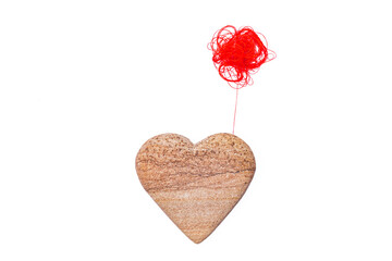 Red spool of yarn and stone heart shaped on white background