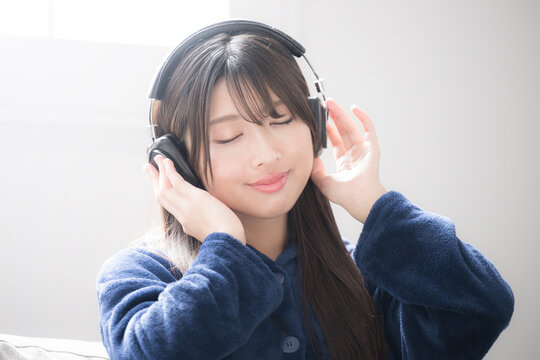Close-up image of a young woman wearing headphones, eyes closed, singing listening to music Copy space