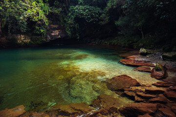 Hidden natural lagoon in Meghalaya, India, with crystal-clear turquoise water, red rock formations,...