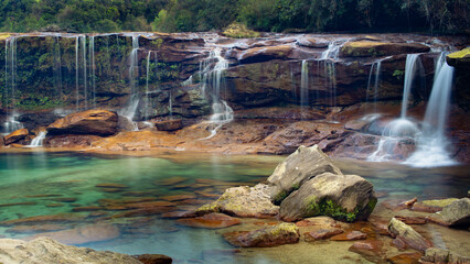 Mawsawa waterfall of cherapunji meghalaya with multiple streams coming down from rocky cliff to crystal clear lagoon.