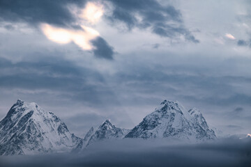 Snow covered Himalayan mountains during sunrise with sunlight breaking through cloud cover in the sky. Panchachuli peaks seen from munsyari uttarakhand.  breaking in.