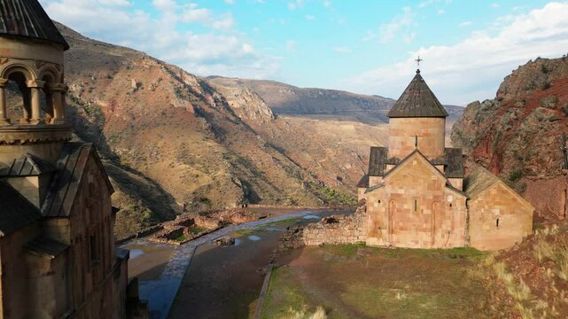 Aerial view passing Noravank monastery complex, 13th-century Armenian monastery. Holy Mother of God church.Noravank at Amaghu. Red cliffs gorge by Arani village. Tourist destination in Armenia