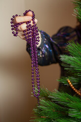 Hands hang garland on Christmas tree close up..