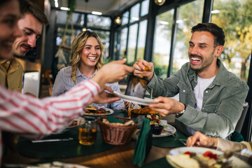 Group of happy friends eating lunch together in a restaurant. They eat delicious salads and...