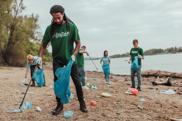 Volunteers collecting trash on river bank: environmental cleanup