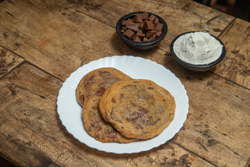 Chocolate chip cookie, Chocolate cookie with chocolate cubes and ice cream flavor of vanilla, Chocolate cookie placed in a wooden dining table