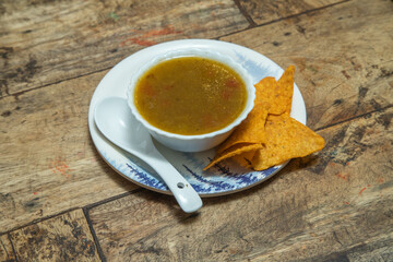 Soups in a white bowl with spicy chips, soups in a wooden dining table