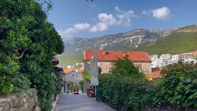 Scenic Mediterranean Alleyway with Traditional Stone Buildings and Mountain Views in Montenegro near Przno Beach, Capturing Calming Rhythms in a Static Shot