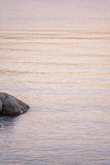 rock and smooth and small waves on the sea reflecting sunset light