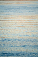 smooth and small waves on the sea reflecting sunset light