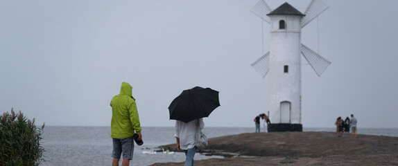 RAINY WEATHER - Woman with umbrella walking by the sea
