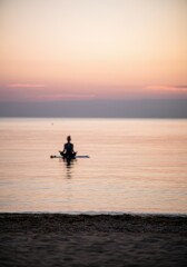 Fototapeta premium Serene meditation at sunset on a paddleboard by tranquil sea horizon