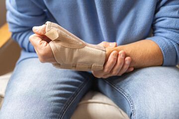 Close-Up Of Injured Hand Wearing Wrist Brace For Pain Relief, Recovery And Rehabilitation –...