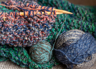 unfinished knitting, skeins of colored woolen yarn, needlework concept, ball of woolen yarn, wooden needles