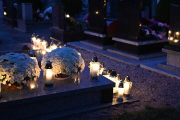 Candle lights on graves and tombstones at a cemetery in Poland during All Saints Day, Zaduszki day,...