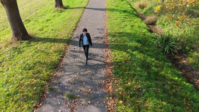 Woman walking on a autumn yellow path from multiple perspectives, drone view from the top