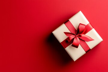 White box with a red bow on top of a red background. The box is a gift and the red background suggests a festive mood