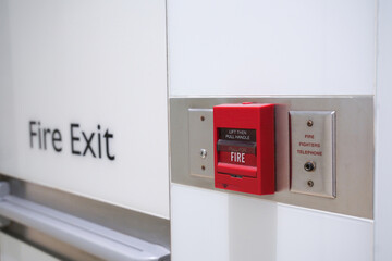 Red fire alarm and exit sign in building corridor