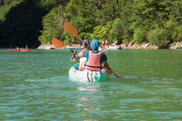 A man and woman canoe on Lake Verdon in southern France on a summer day.