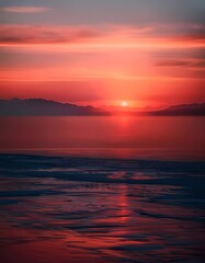 Obraz premium Stunning Sunset Over Calm Ocean with Mountain Silhouettes in the Background
