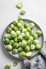 Fresh brussels sprouts in a plate on a light gray background with napkin. Vegetarian healthy food concept.