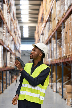 Blue-collar employee scanning shipments with barcode reader in logistics center