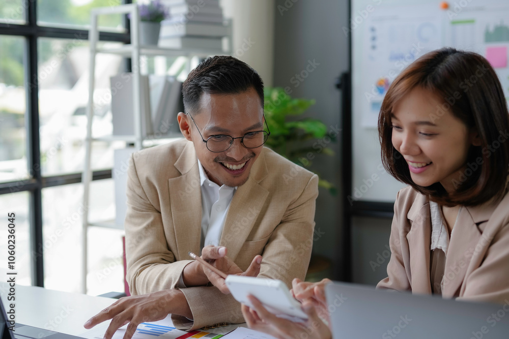 Wall mural two happy business professionals smiling and discussing financial data while working together in mod