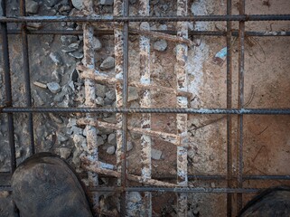 The image shows a close-up view of a concrete reinforcement structure. Rebar forms a grid pattern, providing strength. Concrete surrounds the rebar for compressive strength and corrosion protection. 