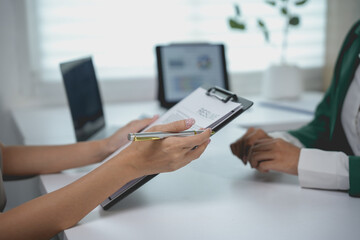Businesswoman holding a document and a pen during a working meeting with a colleague