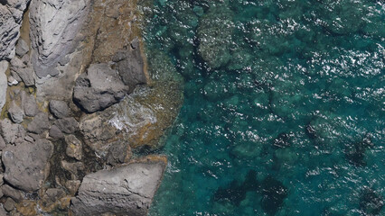 Top-down shot of beautiful emerald-colored clear seawater on a Mediterranean rock beach