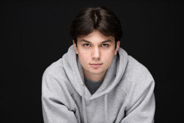 A Young Man in a Gray Hoodie Poses for a Portrait in a Studio Setting, Captured With a Neutral Background and Focused Expression