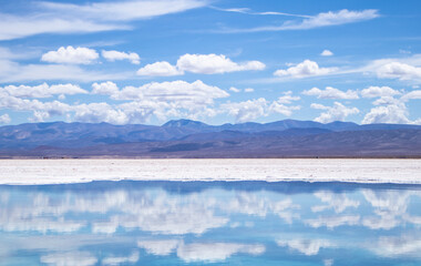 Spectacular view of a blue sky with some white clouds reflected on a lake in the Salinas Grandes of Argentina on a sunny day.