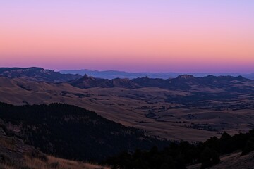 Fototapeta premium Vale de Montanha ao Anoitecer com Céu Suave em Tons de Rosa e Roxo