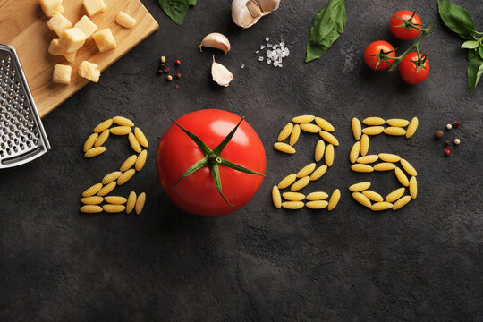 Numbers 2025 made of pasta and tomato on a dark stone background. A culinary idea for the new year.