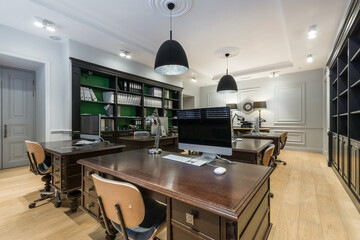 Open office space in neoclassical style. Comfortable desks made of dark wood, filing cabinets..
